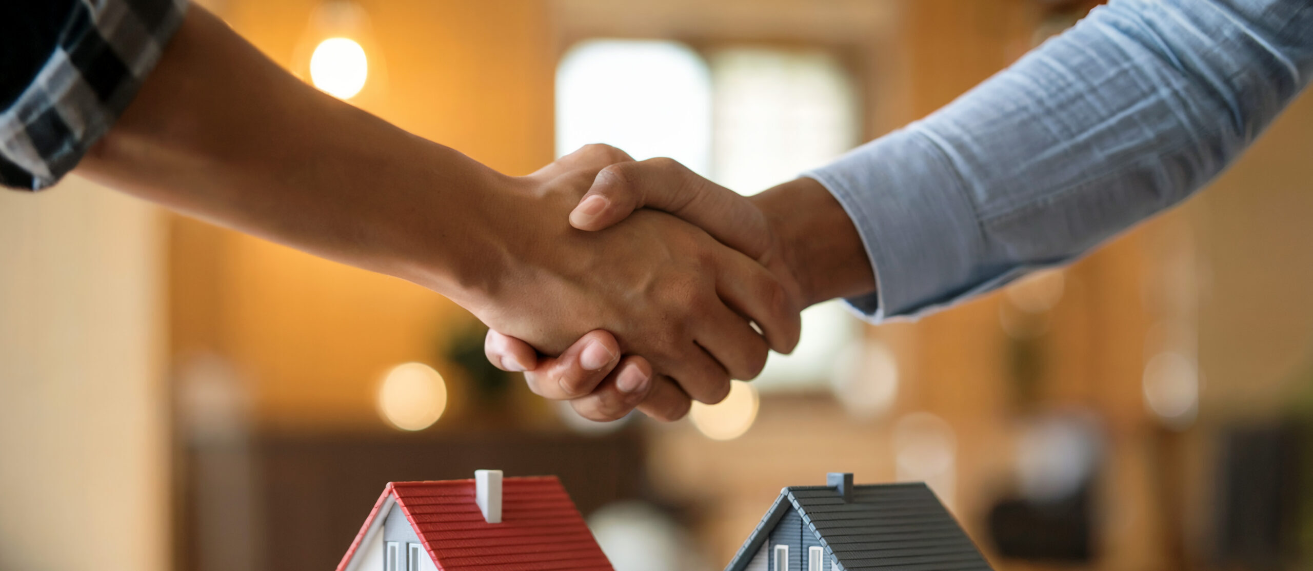 real-estate-deal-shaking-hands-miniature-houses
